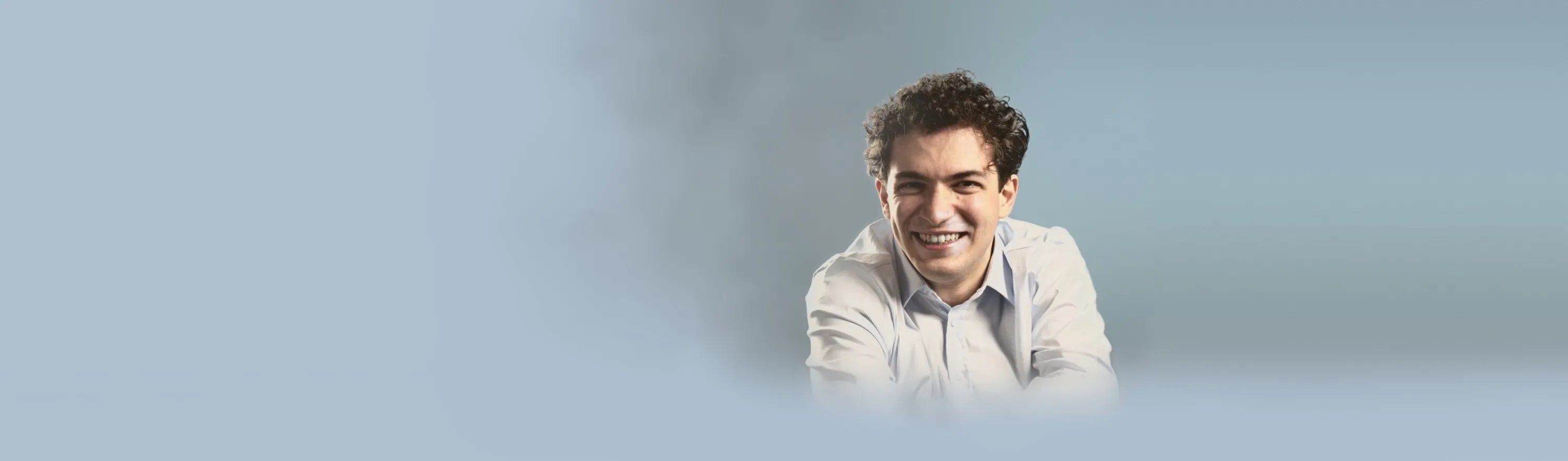 Baritone Biran Özgür Sariyer, studio portrait, light blue shirt, smiling