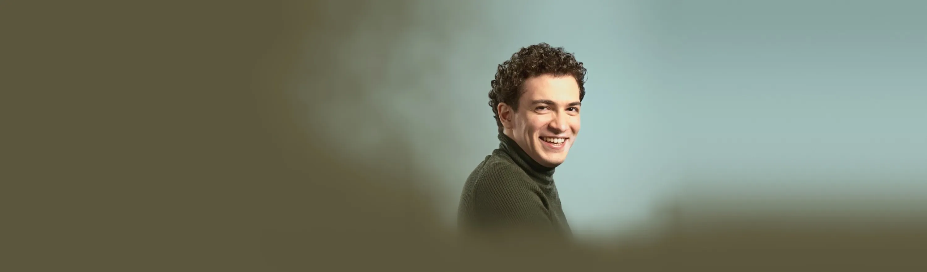 Baritone Biran Özgür Sariyer, studio portrait, smiling, green turtleneck