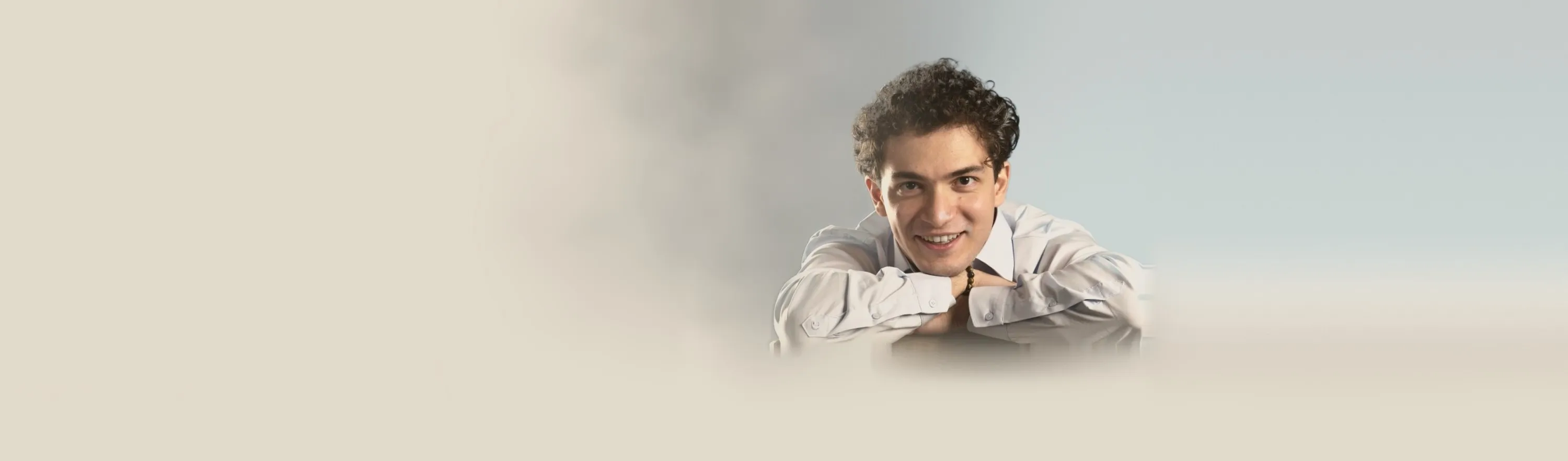 Baritone Biran Özgür Sariyer, studio portrait, leaning on a chair, smiling