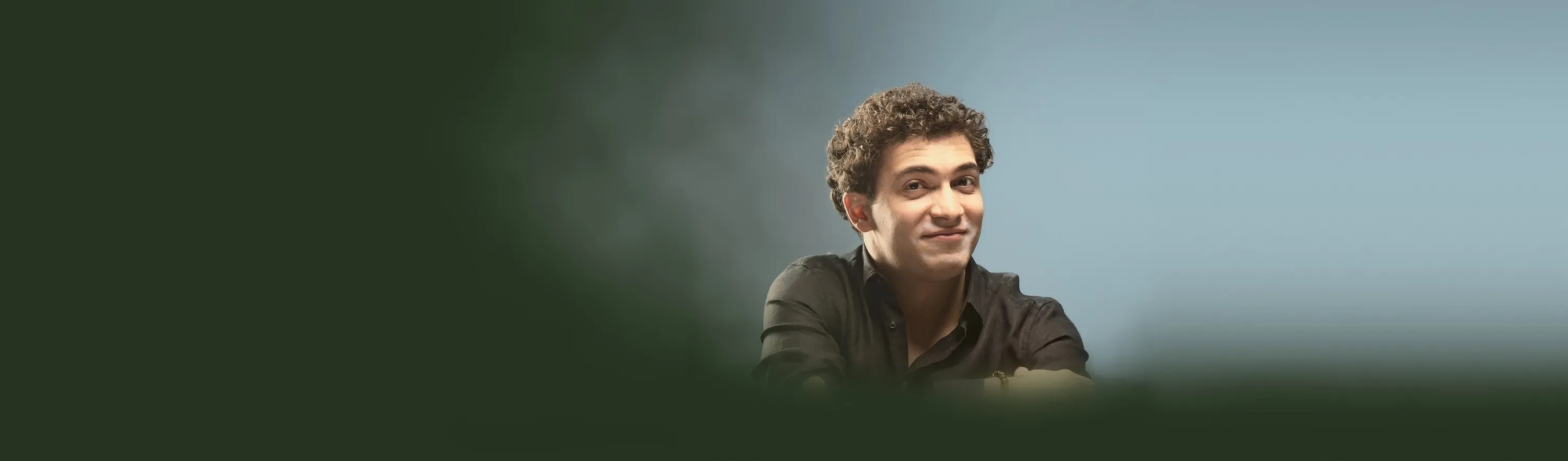 Baritone Biran Özgür Sariyer, studio portrait, black shirt, smiling