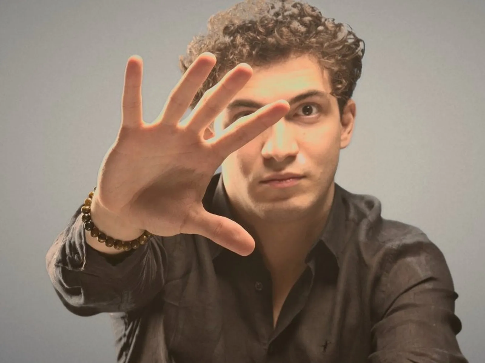 Baritone Biran Özgür Sariyer, studio portrait, hand stretched towards the camera