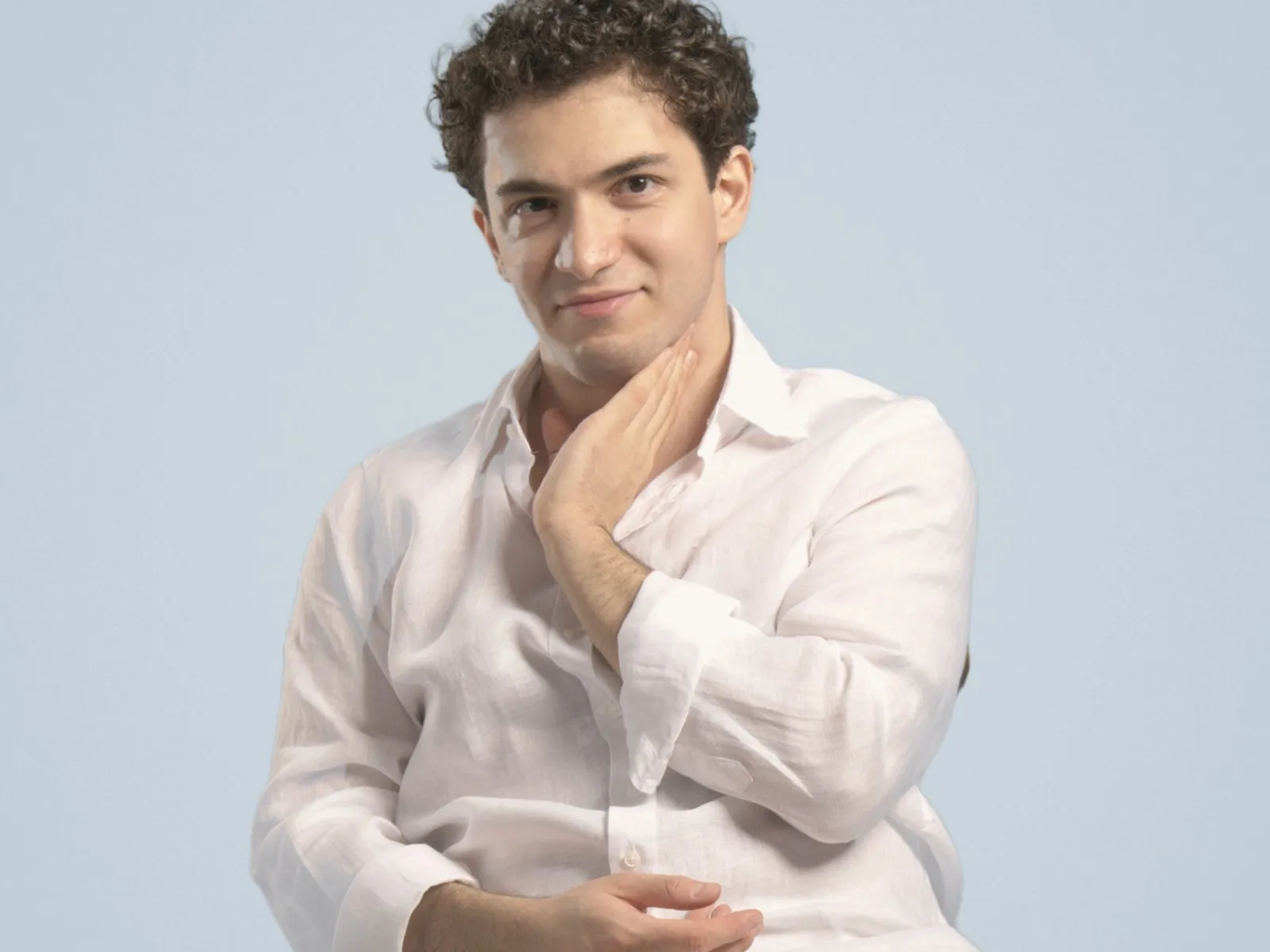 Baritone Biran Özgür Sariyer, studio portrait, seated, hand at his chin
