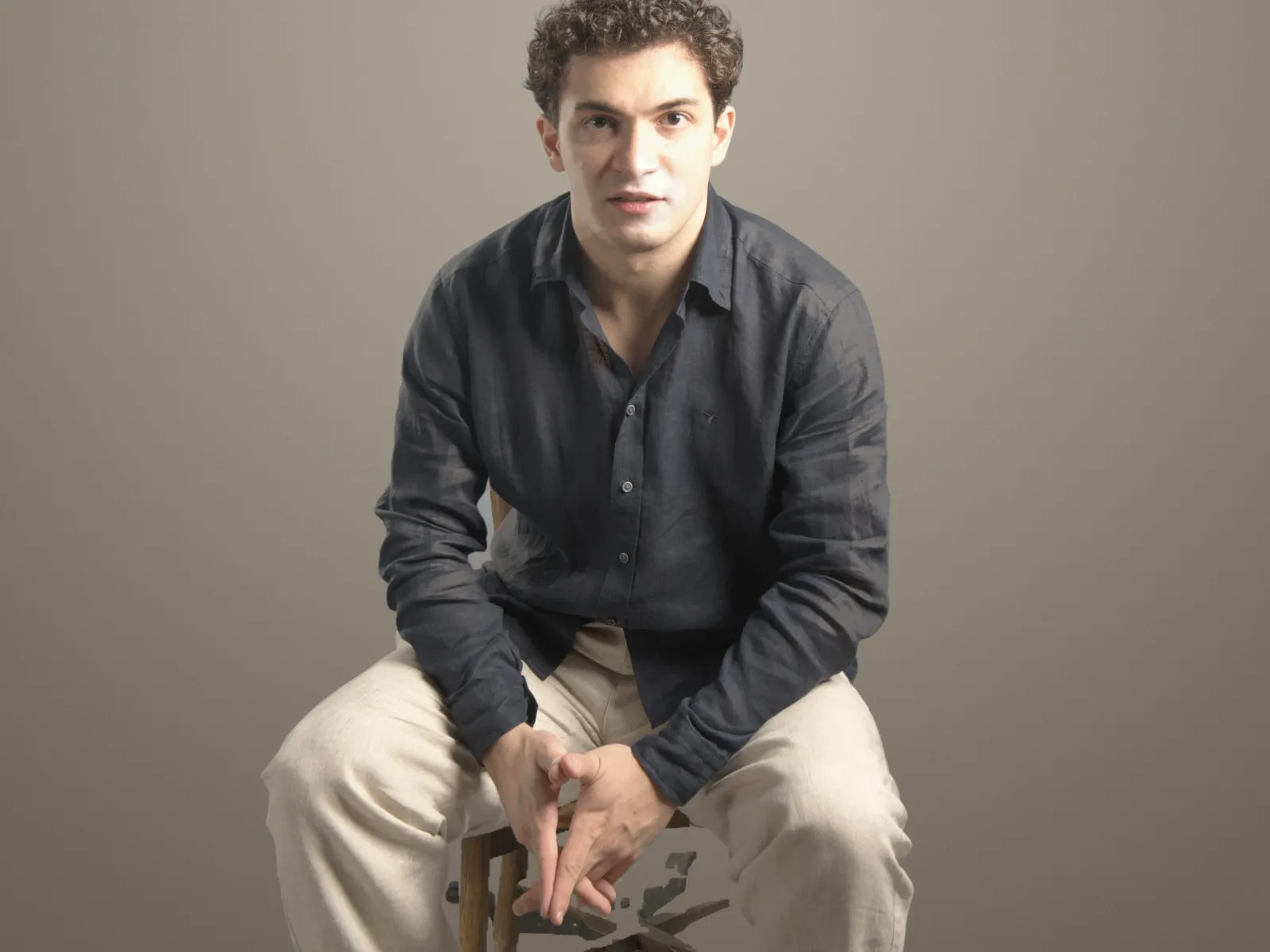 Baritone Biran Özgür Sariyer, studio portrait, seated, navy shirt
