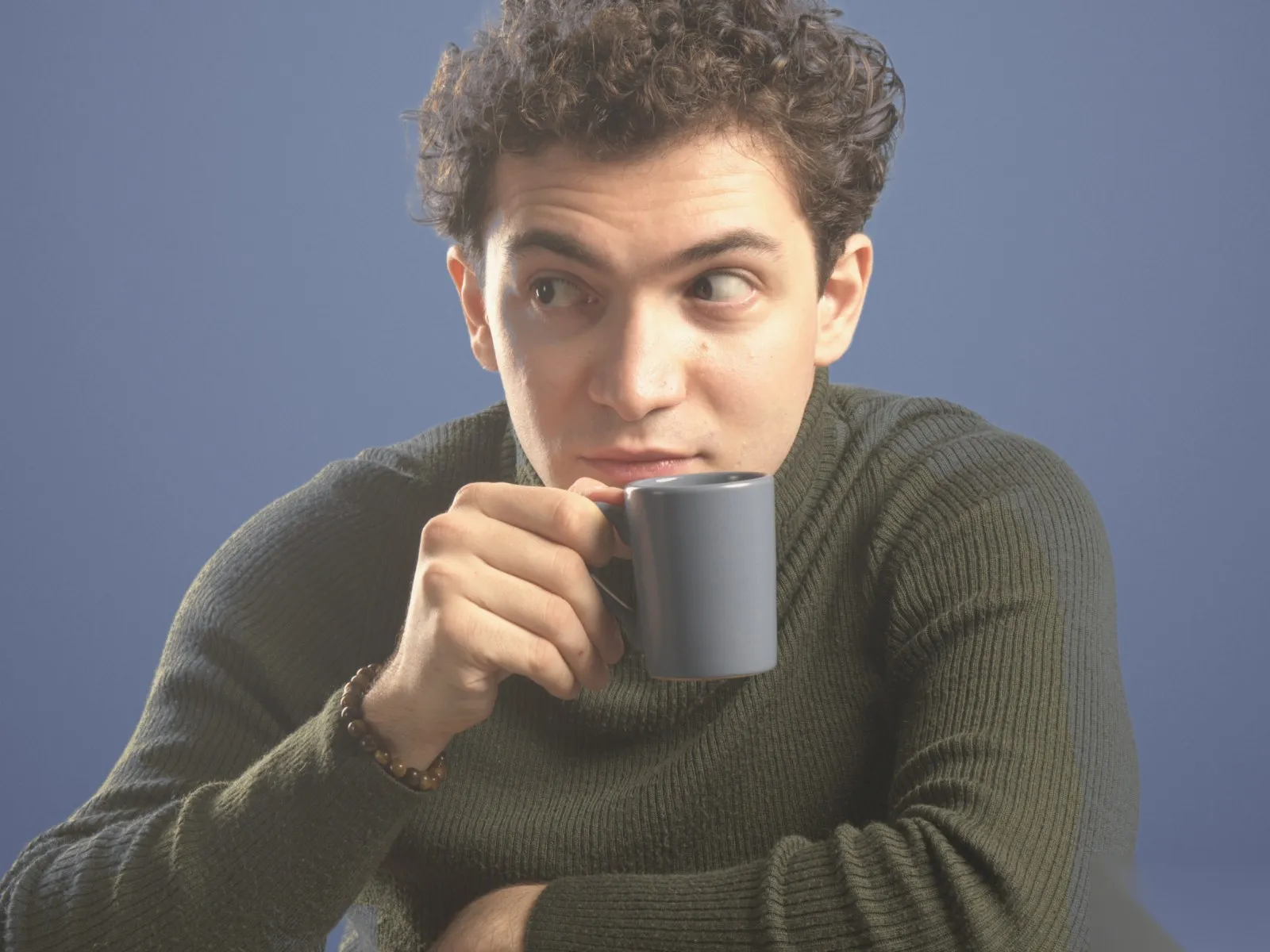 Baritone Biran Özgür Sariyer, studio portrait, with a cup, looking aside