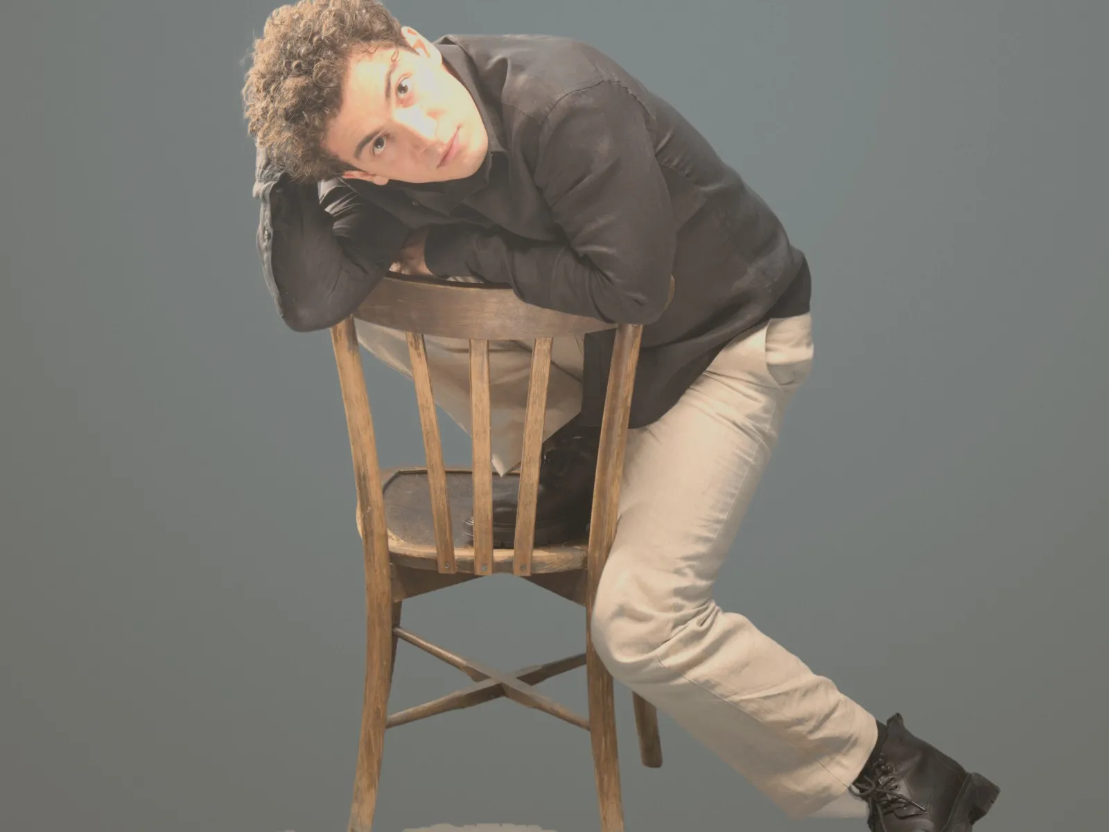 Baritone Biran Özgür Sariyer, studio portrait, resting on a chair, black shirt