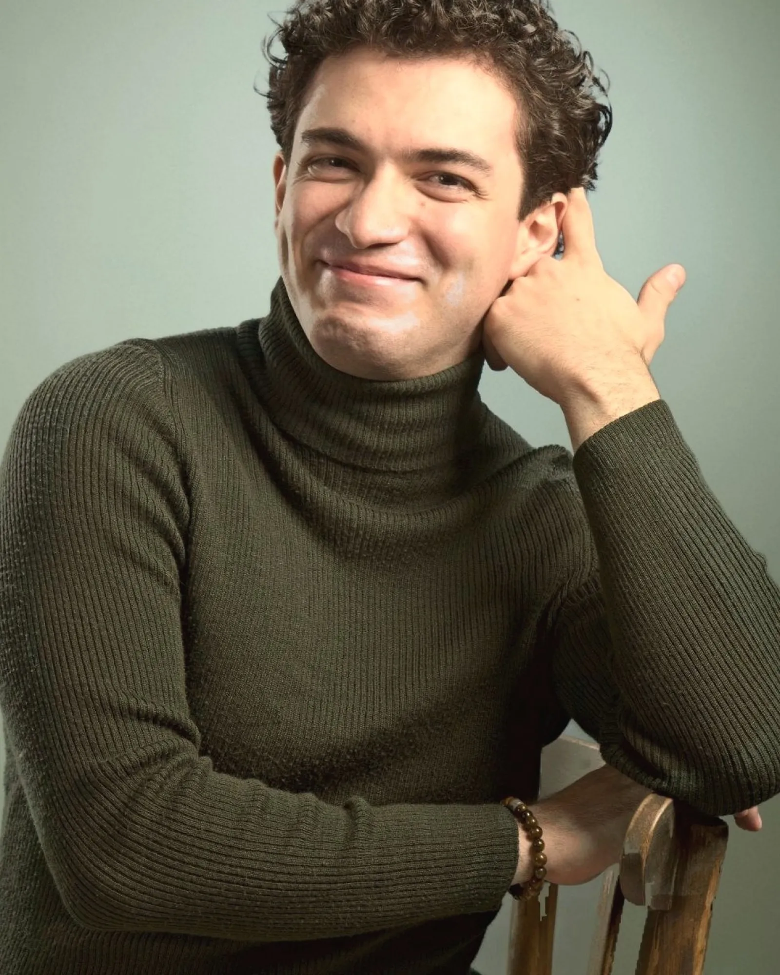 Baritone Biran Özgür Sariyer, studio portrait, smiling, hand at his ear