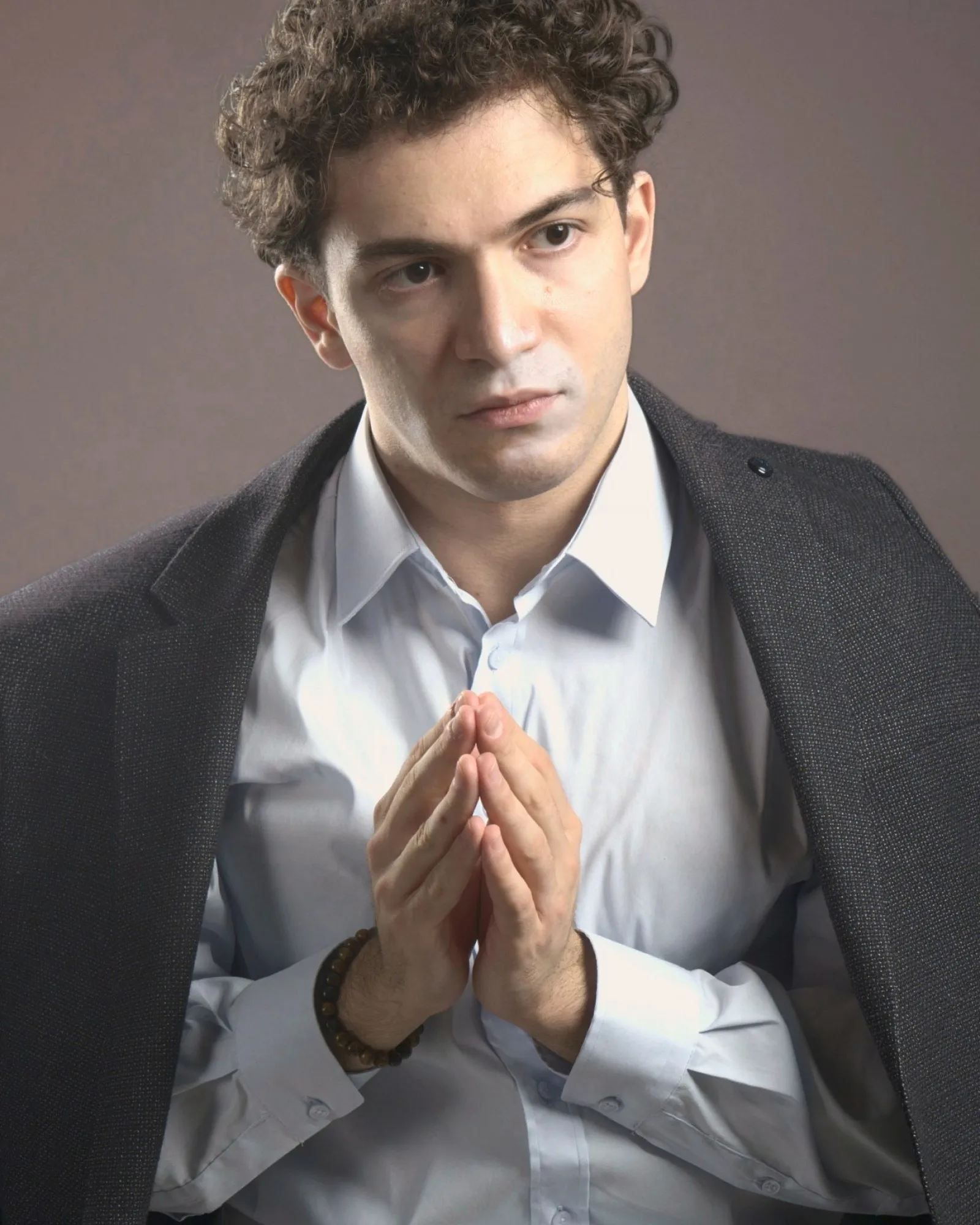 Baritone Biran Özgür Sariyer, studio portrait, hands folded