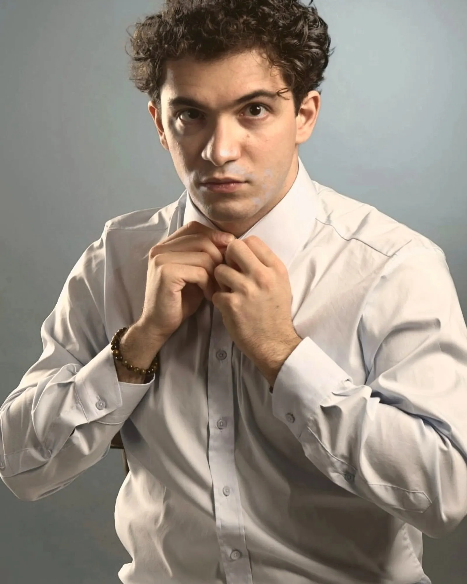 Baritone Biran Özgür Sariyer, studio portrait, buttoning his shirt