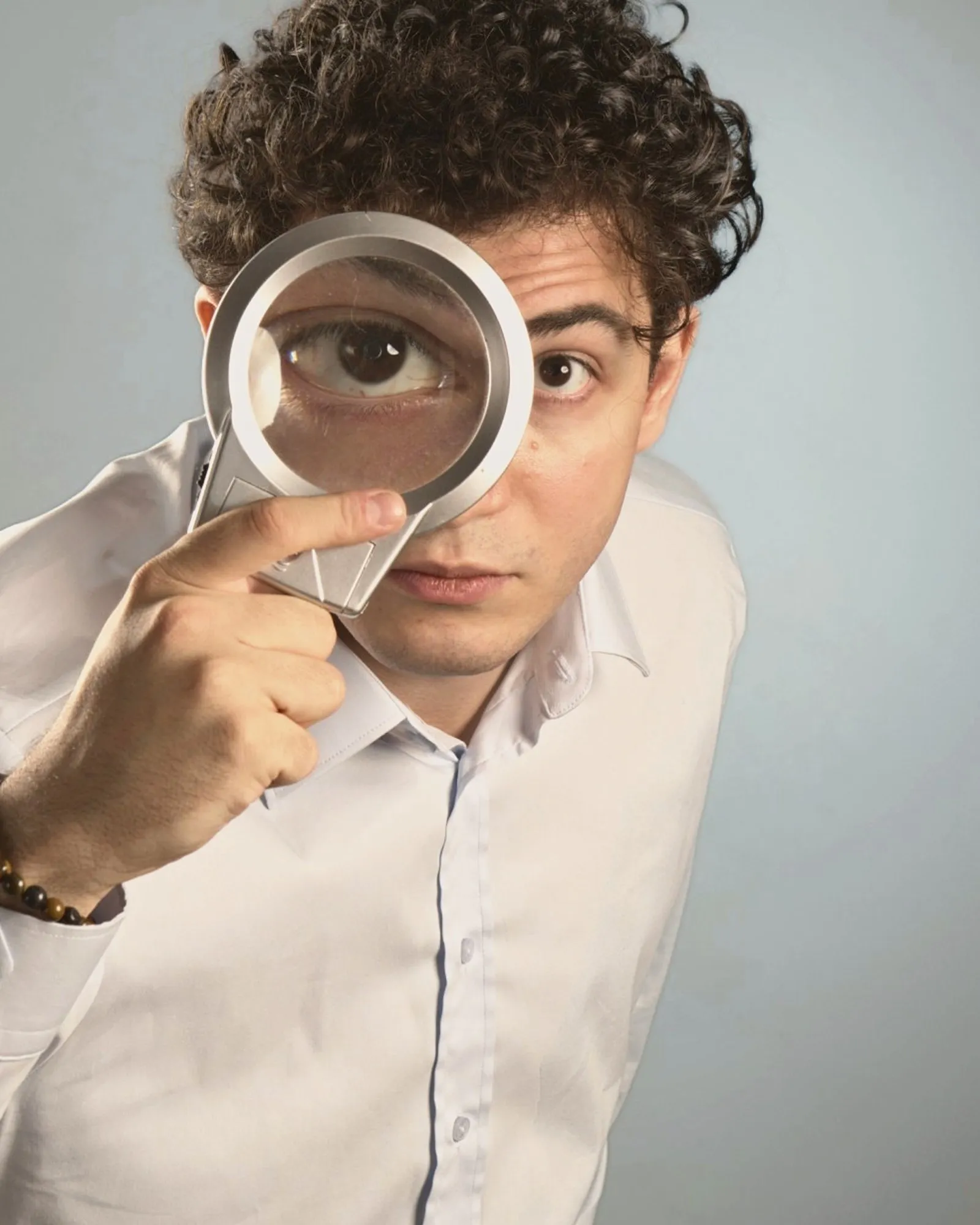 Baritone Biran Özgür Sariyer, studio portrait, with a magnifying glass