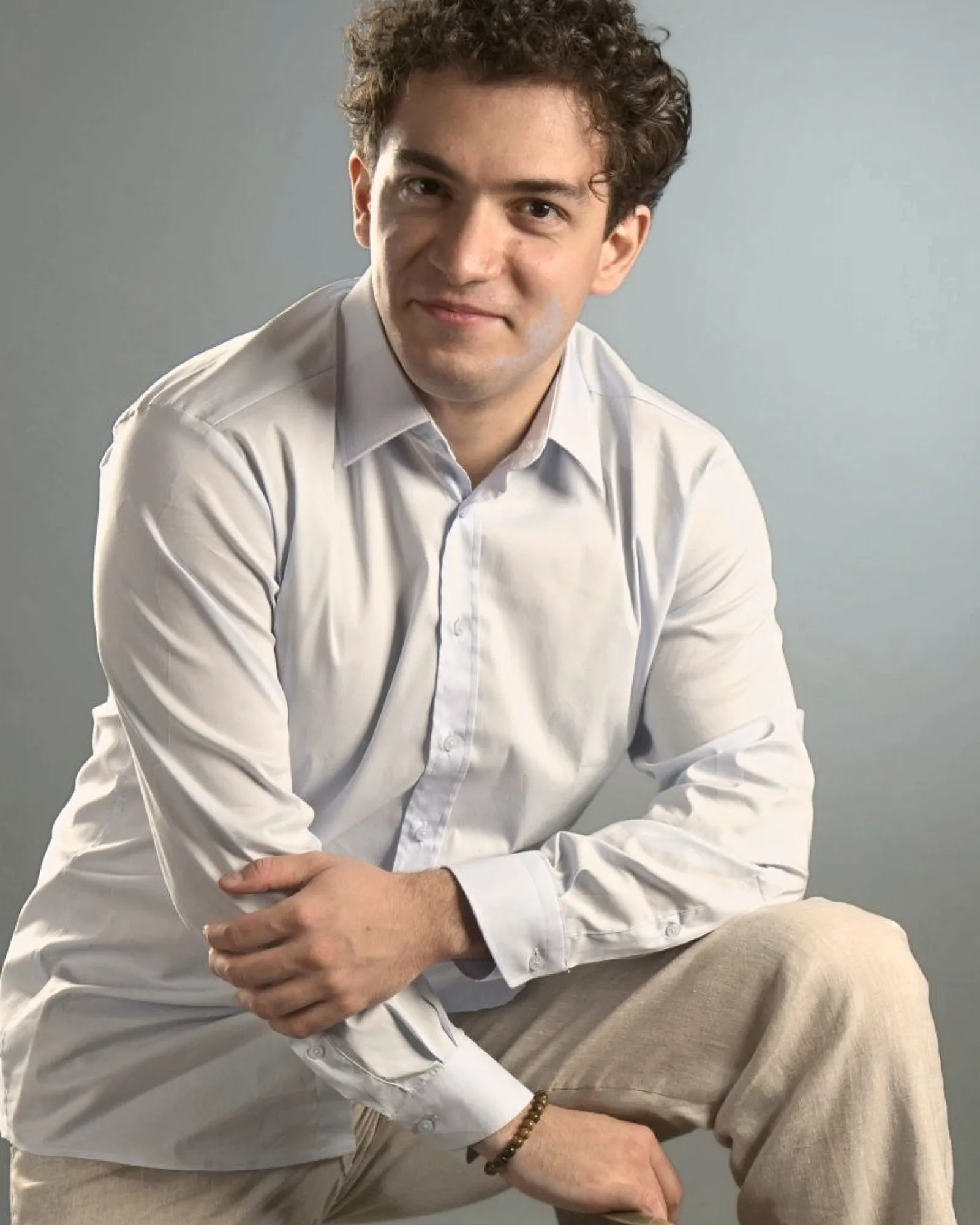 Baritone Biran Özgür Sariyer, studio portrait, standing, foot on a chair